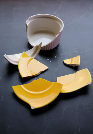 Broken white and yellow pottery scattered on kitchen countertopの写真素材