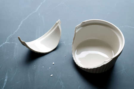 Broken white ceramic baking bowl with fragments on black marble kitchen counter topの写真素材