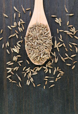 Top View of Dried Cumin Seeds on Wooden Spoon with Some Scattered on the Tableの写真素材