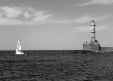 Historic Lighthouse of the Old Port of Chania with a Sailing Boat, Crete Island, Greece in Monochromeの写真素材