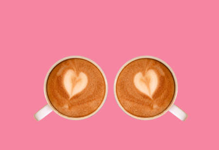 Pair of Heart Shaped Latte Art Cappuccino Coffee Isolated on Flamingo Pink Backgroundの写真素材