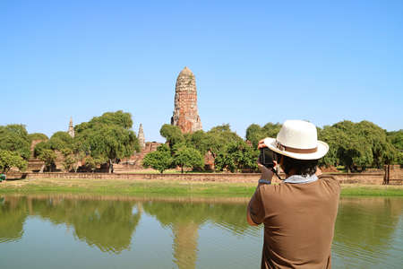 Man Taking Photos of the Medieval Prang of Wat Phra Ram Temple Ruins in Ayutthaya Historical Park,...