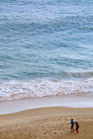 Aerial view of people jogging on the sandy beach in the morningの写真素材