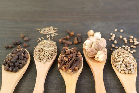 Closeup of Assortment of Spices in Wooden Spoons on Dark Brown Backdropの写真素材