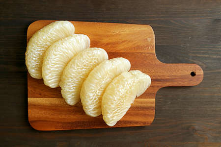 Sweet and Juicy Peeled Fresh Pomelo Fruit Segments on Wooden Cutting Board