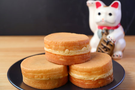 Stack of Imagawayaki or Obanyaki, Japanese Traditional Filling Pan Cakes with Beckoning Cat Maneki-nekoの写真素材