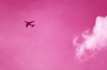 Pop art surreal image of jet plane flying on pink skyの写真素材