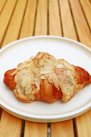 Delectable French Almond Croissant Pastry Served on Wooden Tableの写真素材