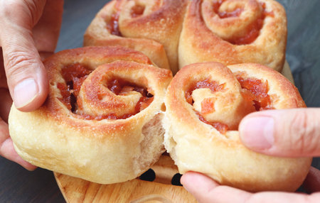 Closeup of Hands Splitting Freshly Baked Apple Cinnamon Rolls