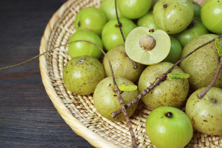 Heap of Fresh Indian Gooseberries or Amla in a Basket on Black Wooden Tableの写真素材