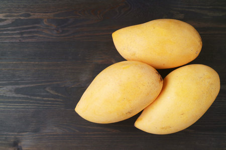 Heap of Fresh Ripe Mango Fruits Isolated on Black Wooden Backgroundの写真素材