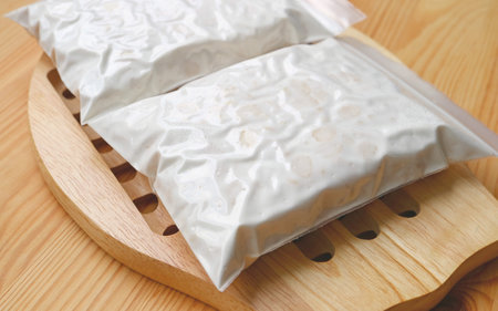 Closeup of Tempeh after Soybeans Fermented in Perforated Bags Covered with Thick and Dense White Myceliumの写真素材