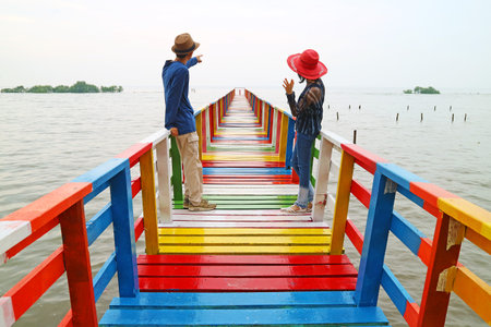 Happy Couple Relaxing Together on a Multi Colored Wooden Boardwalkの写真素材