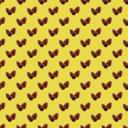 Seamless pattern of natural dried pine cones on golden yellow background