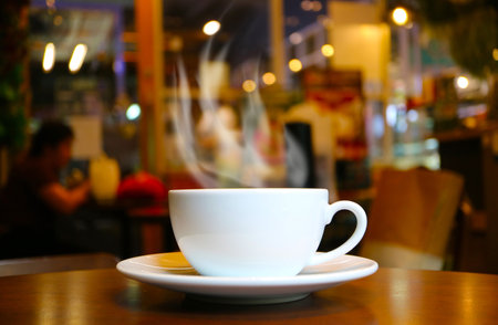 Closeup of a cup of hot coffee with rising smoke on wooden tableの写真素材