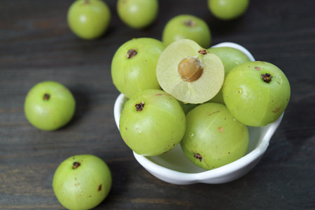 Closeup of Cut Fresh Amla Berry with Whole Fruits Scattered Aroundの写真素材