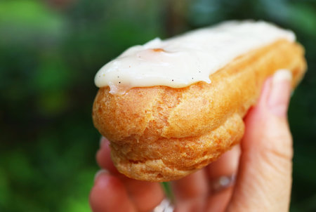 Closeup of Mouthwatering Vanilla Eclair in Hand