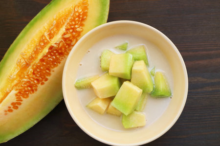 Thai Melon in Chilled Sweetened Coconut Milk with a Slice of Fresh Fruit on Black Wooden Backgroundの写真素材