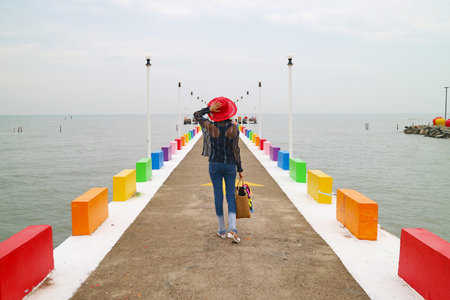 Woman in Red Hat Walking on the Colorful Pier