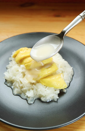 Spoon Adding Coconut Milk to Delectable Thai Sticky Rice with Durian Called Kao Niaow Turianの写真素材