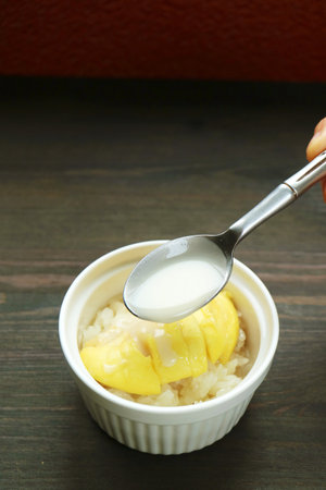Spoon Adding Coconut Milk into a Delectable Thai Sticky Rice with Durian Called Kao Niaow Turianの写真素材