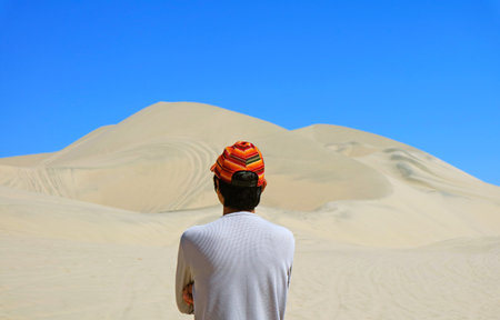 Man looking at the amazing sand dunes of Huacachina desert, Ica region, Peru, South Americaの写真素材