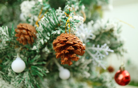 Closeup of a Dried Pine Cone Ornament Hanging on a Snow Covering Christmas Treeの写真素材
