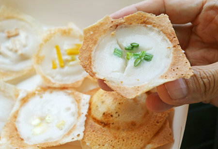 Hand Picking a Kanom Krok Spring Onion Topping, Thai coconut milk pancake which one of the popular street food in Thailandの写真素材