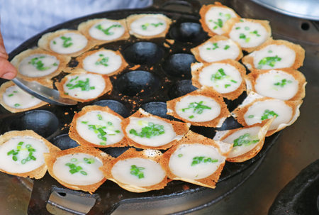 vendor taking Kanom Krok, popular Thai coconut milk pancake out from the pan when ready to serveの写真素材