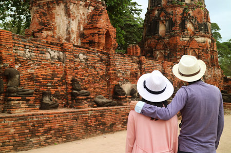Couple Being Impressed by Group of Headless Buddha Images Ruins in Wat Mahathat Ancient Temple in Ayutthaya Historical Park, Thailandの写真素材
