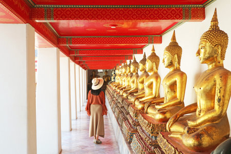 Female Visiting the Cloister with a Large Group of Seated Buddha Images in Wat Pho or Temple of the Reclining Buddha, Bangkok Old City, Thailandの写真素材