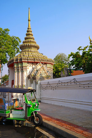 Tuk-tuk taxi parking on the street in front of the ornate gate of Wat Pho or Temple of the Reclining Buddha, Bangkok, Thailandの写真素材