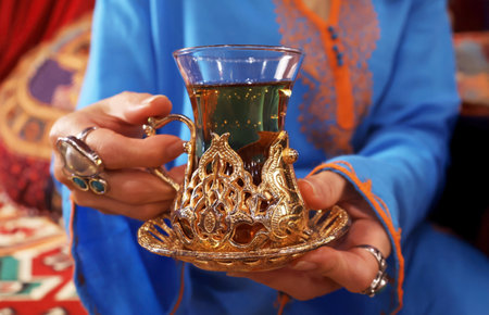 Closeup of Hand Holding a Hot Turkish Herbal Tea in an Elaborated Tulip-shaped Glassの写真素材