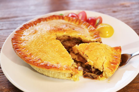 Delectable Golden Brown Beef Pie Served on Wooden Tableの写真素材