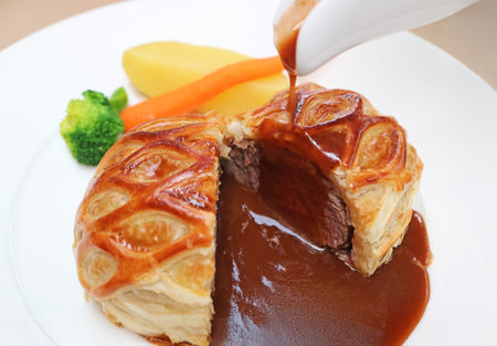 Closeup of Mouthwatering Beef Wellington Pouring with Red Wine Sauceの写真素材