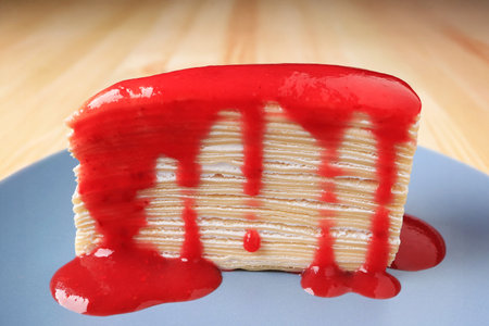 Closeup a Slice of Mouthwatering Vanilla Mille Crepe Cake with Raspberry Sauceの写真素材