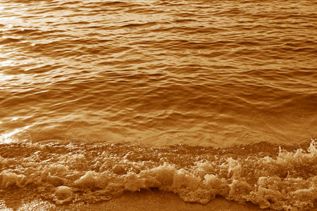 Golden waves in sunlight splashing on the beachの写真素材