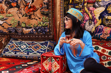 Woman Holding a Glass of Hot Turkish Herbal Tea in an Elaborated Tulip-shaped Glassの写真素材