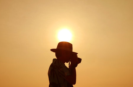 Silhouette of a man taking photos on a sunny dayの写真素材