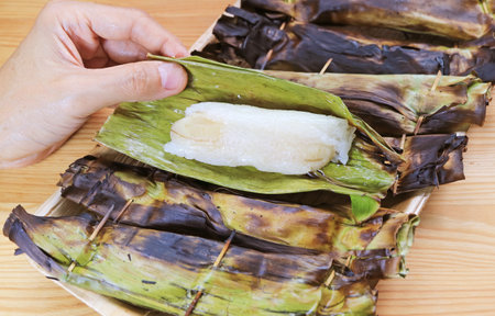 Hand unwrapped Banana Leaf of Khao Niao Ping, a Charcoal Grilled Thai Sweetened Sticky Rice with Fillingsの写真素材