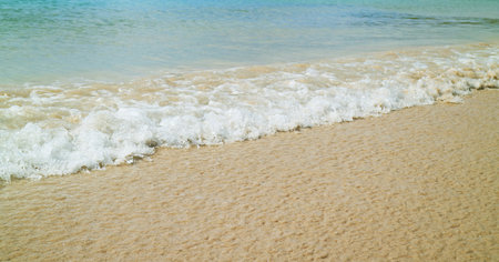 Waves of the blue ocean clashing on the sandy beachの写真素材
