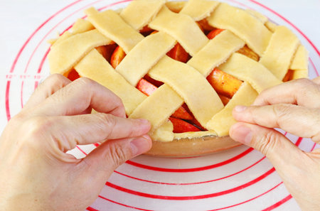 Weaving cut doughs on pie plate for lattice top crust of apple pieの写真素材