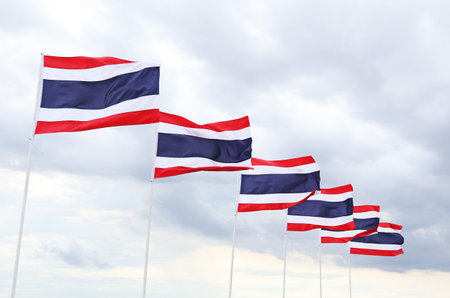 Row of Flags of the Kingdom of Thailand Called THONG TRAI RONG, Meaning 'Tricolor Flag' Waving on Cloudy Skyの写真素材