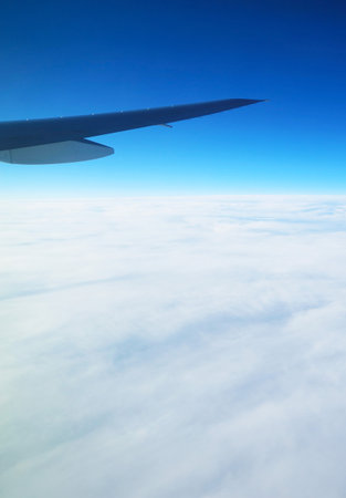 Plane wing on vivid blue sky with sea of clouds view from plane window during flightの写真素材