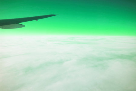 Surreal pop art of Airplane wing on the green sky with white clouds view from airplane during flightの写真素材