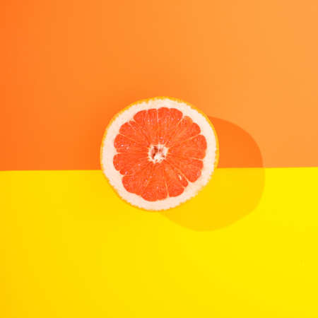 A slice of fresh grapefruit on a colorful background.Exotic food minimal concept.