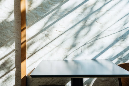 Soft sunlight casting shadows on a table in a minimalist settingの素材