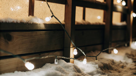 Cozy winter decor with warm fairy lights glowing on a snowy surfaceの素材