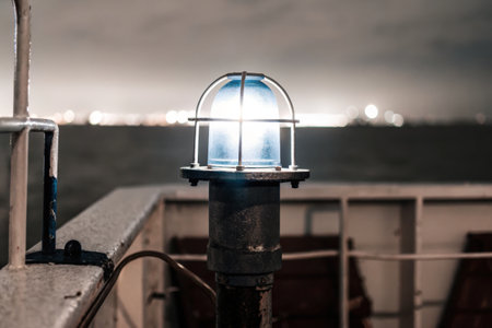Industrial blue light fixture on a dock with ocean background at duskの素材