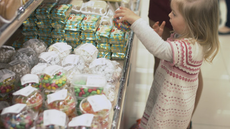 Mother and daughter choosing dragees in packages in the sweets departmentの写真素材